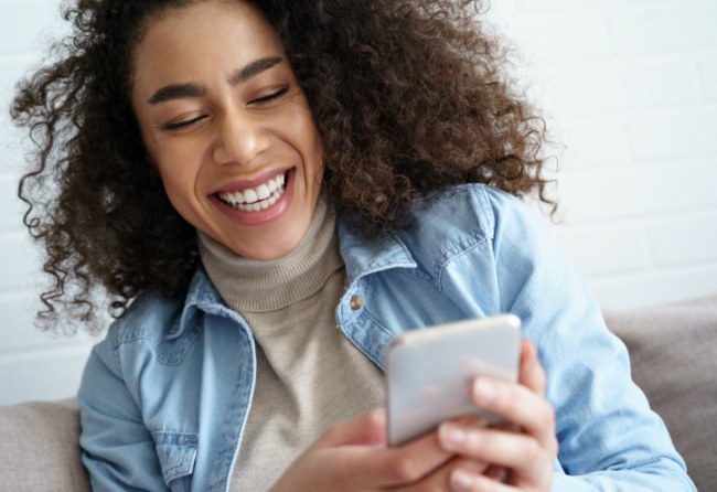 Black African American woman smiling and looking at her cell phone
